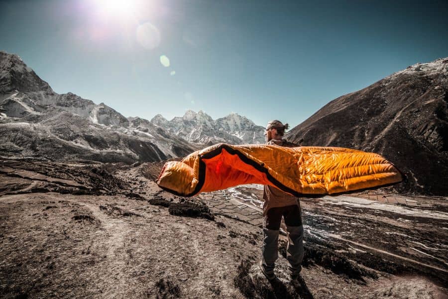A man with a sleeping bag in the mountains